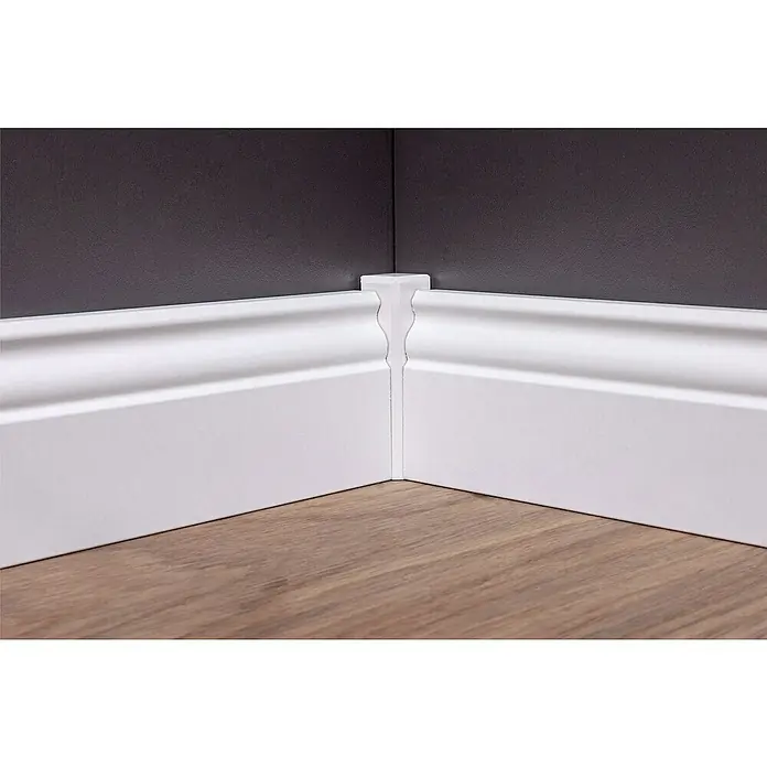 Sockelleiste - 240 x 1,9 x 7 cm, MDF, Profiliert - Nahaufnahme einer weißen Sockelleiste, die einen eleganten Übergang zwischen dunkler Wand und hellem Holzboden bildet.
