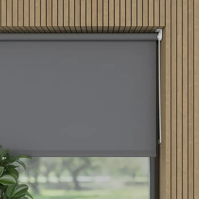 Expo Ambiente Rollo Mini - B x H: 75 x 150 cm, Grau, Uni, Tageslichtdurchlässig - Ein graues Rollo ist heruntergelassen und verdeckt ein Fenster, das auf eine grüne Außenanlage blickt. Das Rollo ist an einer Holzwand montiert.