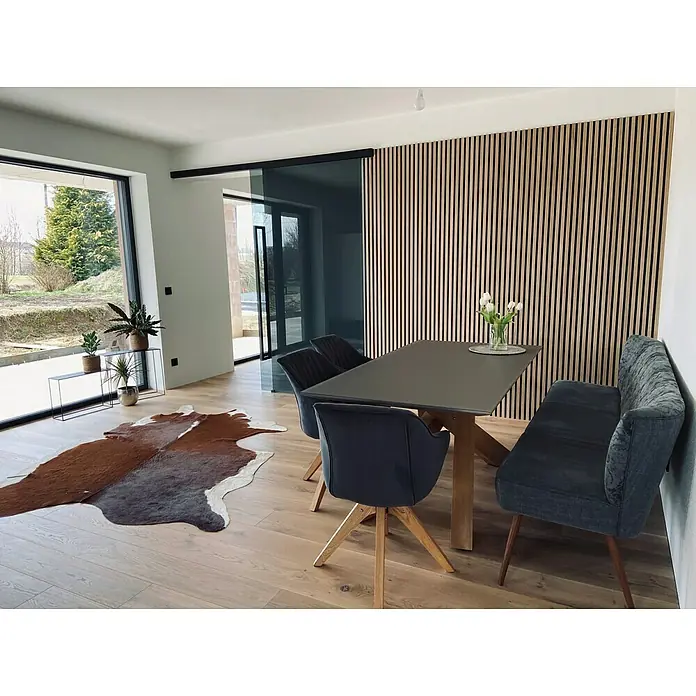 FibroTech Akustikpaneel Proff - Light Oak, L x B x S: 3.000 x 605 x 22 mm - Esszimmer mit Esstisch und Stühlen vor einer stilvollen Holzpaneelwand. Die moderne Einrichtung wird durch natürliches Licht betont.