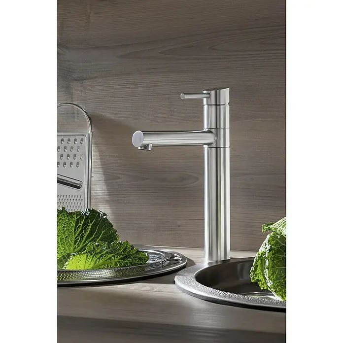 Camargue Spültischarmatur Burgos - Edelstahl, Matt - Nahaufnahme eines modernen Edelstahl-Wasserhahns in einer Küche mit Gemüse und Küchenreibe.