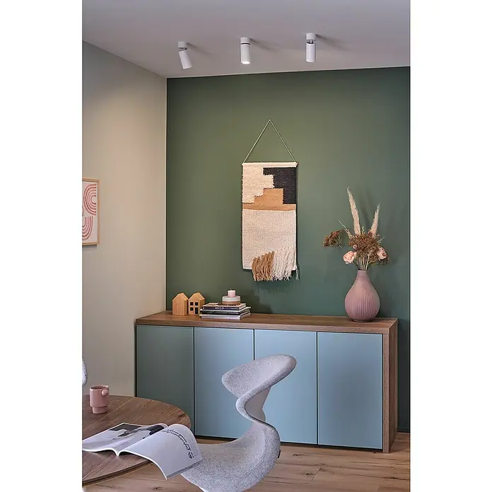 Paulmann LED-Deckenleuchte Turnal Coin - 6 W, Weiß matt, 1 Stk. - Wohnzimmer mit moderner Wanddeko, Sideboard mit Dekoobjekten und einem eleganten Sessel. Die Wand ist in einem satten Grünton gestrichen.