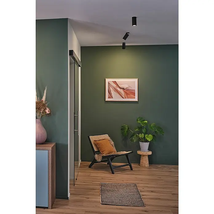 Paulmann LED-Einbauleuchten-Set rund Turnal Coin - 6 W, Schwarz matt, 3 Stk., Warmweiß - Einrichtungsidee mit dunklen Wänden, minimalistischer Kunst, einem Sessel mit Kissen und Akzentbeleuchtung, die eine gemütliche Atmosphäre schafft.
