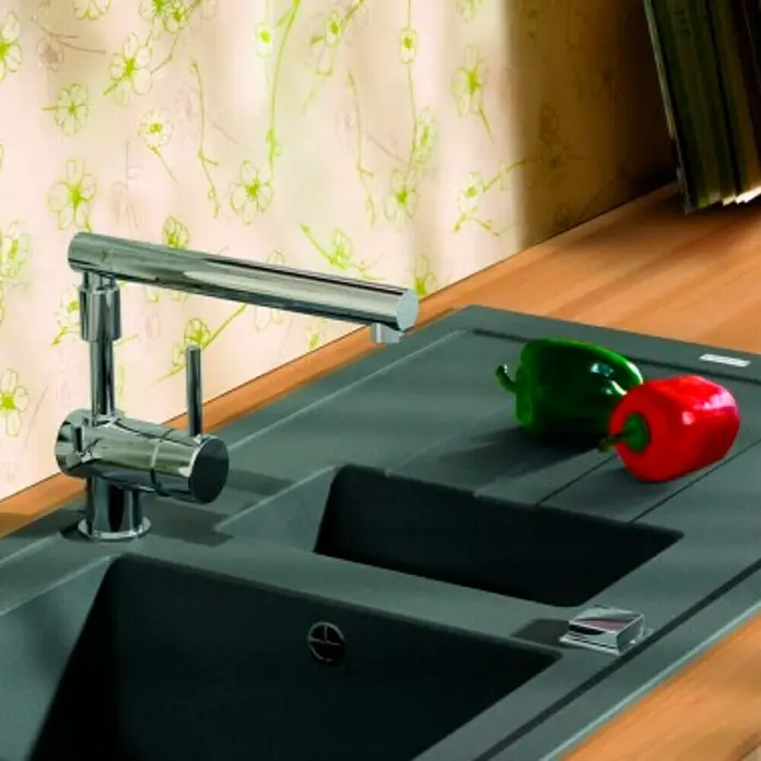 Carea Einbauspüle Tango - 98 x 50 cm, Material Spüle: CAREAlith®, Betongrau - Das Bild zeigt eine moderne Küchenspüle mit einem schwenkbaren Wasserhahn und zwei Paprika.