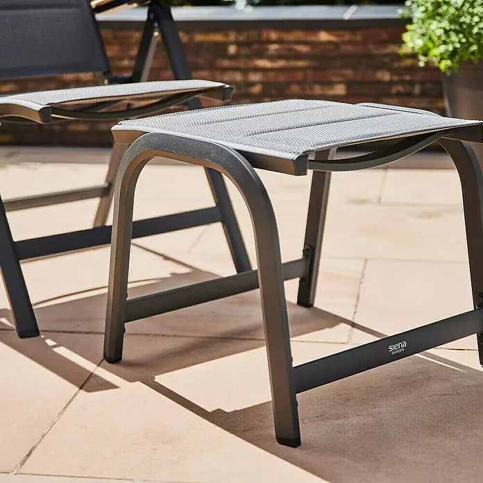 Siena Garden Tesoro GartenhockerB x T x H: 51 x 51 x 43 cm, Anthrazit - Nahaufnahme eines grauen "Siena Garden" Fußhockers aus Metall mit einem gewebten Sitz auf einer Terrasse mit Fliesen.