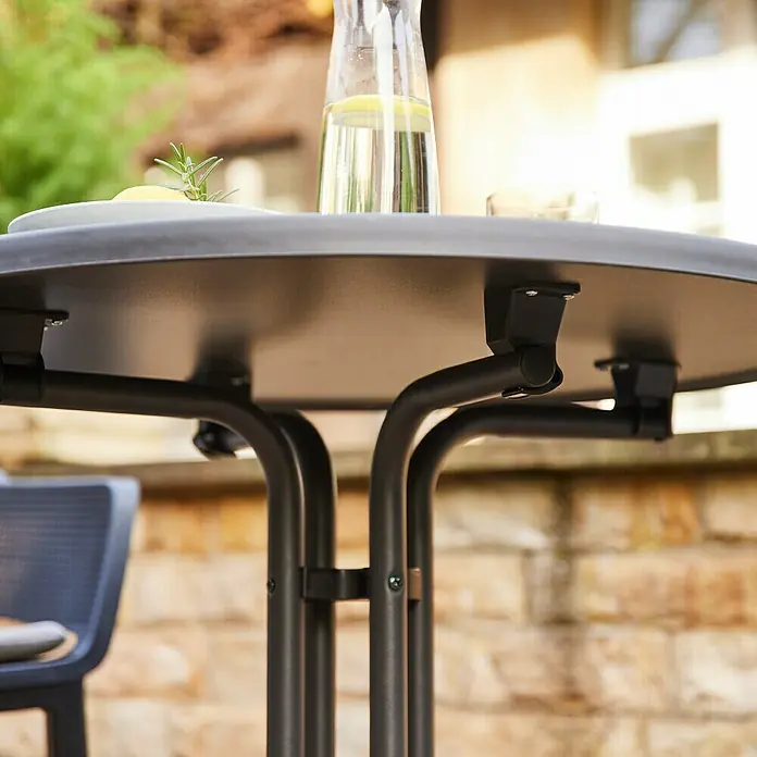 Siena Garden Gartentisch rund Paco - Stahl, Rund, Anthrazit - Nahaufnahme eines schwarzen Gartentisches mit Getränken und Snacks, der Stabilität und Eleganz im Freien vereint.