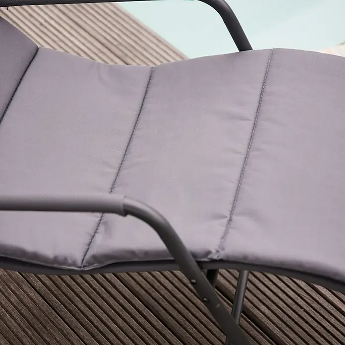 Siena Garden Gartenliege Aliano - Grau, Stahl, Pulverbeschichtet - Detailaufnahme eines grauen Outdoor-Stuhls mit gepolsterter Sitzfläche und Armlehnen auf einer Holzterrasse, ideal für entspannte Stunden im Freien.