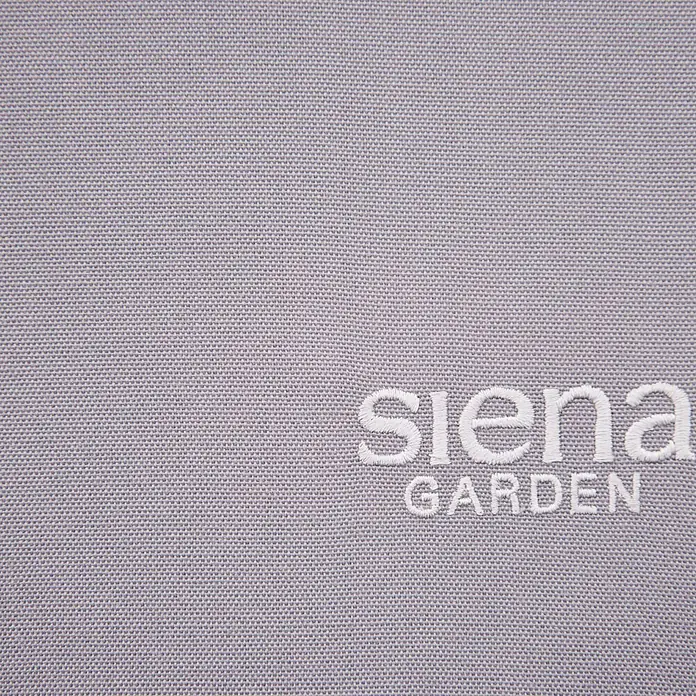 Siena Garden Gartenliege Aliano - Grau, Stahl, Pulverbeschichtet - Nahaufnahme eines Stoffetiketts mit dem Aufdruck "siena GARDEN" in Weiß auf einem strukturierten, violetten Hintergrund.