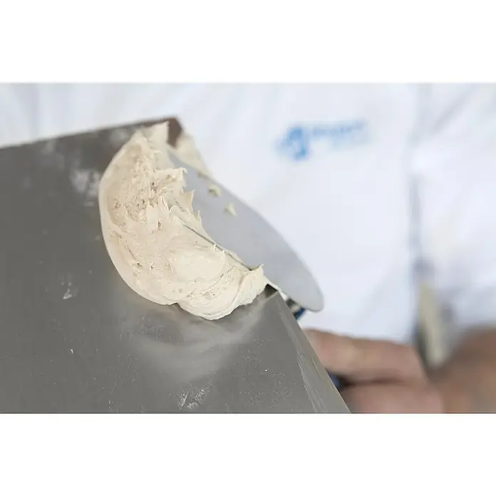 Rigips Fugenspachtel ProMix Plus18 kg, Gebrauchsfertig - Nahaufnahme von Spachtelmasse auf einer Spachtel, die für Reparaturarbeiten verwendet wird. Die helle Textur und das Werkzeug sind deutlich erkennbar.
