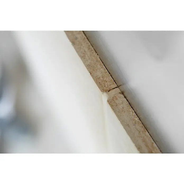 Rigips Rigidur Fugenspachtel Vario - 5 kg - Nahaufnahme einer MDF-Platte mit weißer Oberfläche, die die Materialbeschaffenheit und die Verbindung zweier Teile zeigt.