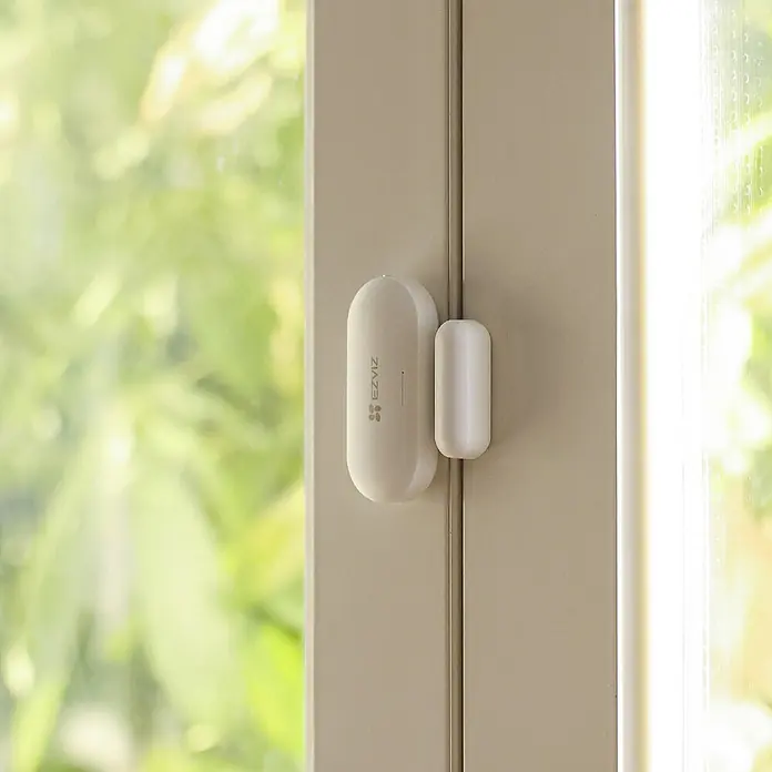 EZVIZ Pack de seguridad Smart Home A3 - 4 pzs., ZigBee 3.0 - Sensor blanco EZVIZ de puerta y ventana montado en marco beige, que garantiza seguridad.