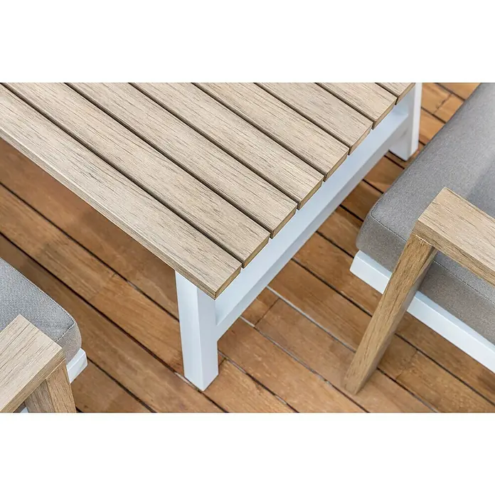 Sunfun Conjunto de muebles Morgana - 4 pzs., Enviro Imitation Wood® / Aluminio, Marrón/Blanco - Primer plano de una mesa de jardín moderna con listones de madera y patas blancas, junto a un sillón lounge gris en una terraza de madera.