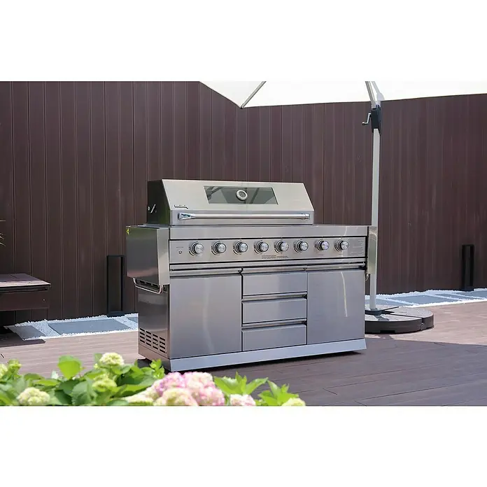 Buschbeck Outdoorküche Bristol - Edelstahl, Silber, Material Grillfläche: Edelstahl, Anzahl Brenner: 6 Stk. - Nahaufnahme eines modernen Edelstahlgrills mit mehreren Brennern, Schubladen und einem Schrank auf einer Terrasse im Freien.