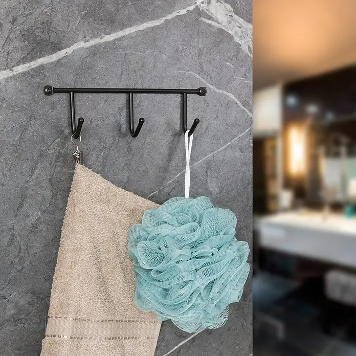 Walteco Hakenleiste - L x B x H: 200 x 35 x 60 mm, Anzahl Haken: 3 Stk., Schwarz - Nahaufnahme einer schwarzen Handtuchstange mit einem beigen Handtuch und einem türkisfarbenen Badeschwamm im Badezimmer.