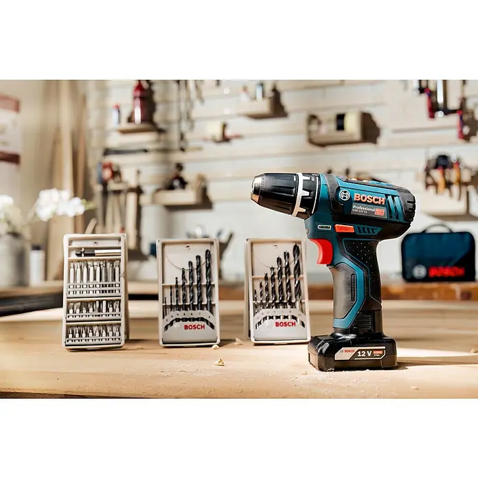 Bosch Professional Akku-Bohrschrauber GSR 12V-15 - 12 V, 2 Akkus, 2 Ah - 4 Ah, 30 Nm - Nahaufnahme eines Bosch Professional GSR 12V-15 Akku-Bohrschraubers mit Zubehör auf einer Werkbank, ideal für professionelle Handwerker.