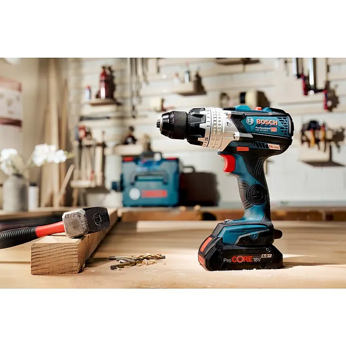 Bosch Professional AMPShare 18V Akku-Schlagbohrschrauber GSB 18V-110 C - 18 V, 2 Akkus, 4 Ah, 110 Nm, Inkl. Koffer - Nahaufnahme eines Bosch Professional Akku-Bohrschraubers auf einer Werkbank, der die robuste Bauweise und das ergonomische Design hervorhebt.