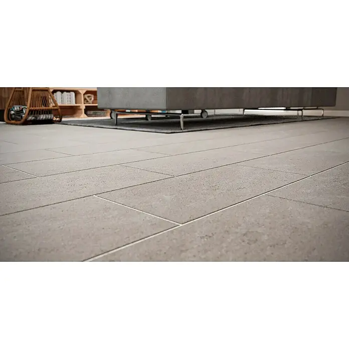 Feinsteinzeugfliese Beton - 30 x 60 cm, Grau, Matt - Nahaufnahme des Bodenbelags mit hellgrauen Fliesen, verlegt im Langformat, sowie ein Tisch mit Teppich und ein Regal im Hintergrund.