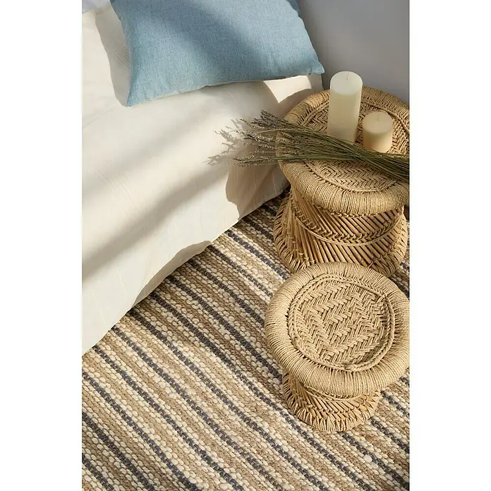 Alfombra de yute Rayas - Natural/crudo, 150 x 80 cm - Primer plano de una escena de dormitorio con dos mesitas auxiliares decorativas de mimbre, velas y una alfombra de rayas, creando un ambiente acogedor.