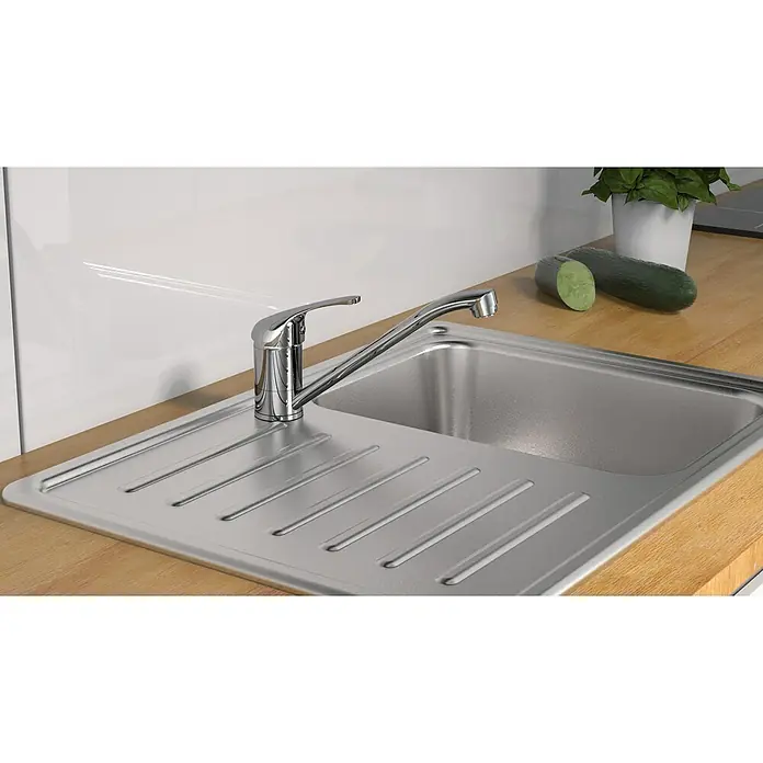 Camargue Spültischarmatur Ultra -  - Nahaufnahme einer Edelstahlspüle mit Wasserhahn auf einer hölzernen Arbeitsplatte, neben der eine Zucchini und ein Topf mit Kräutern stehen.