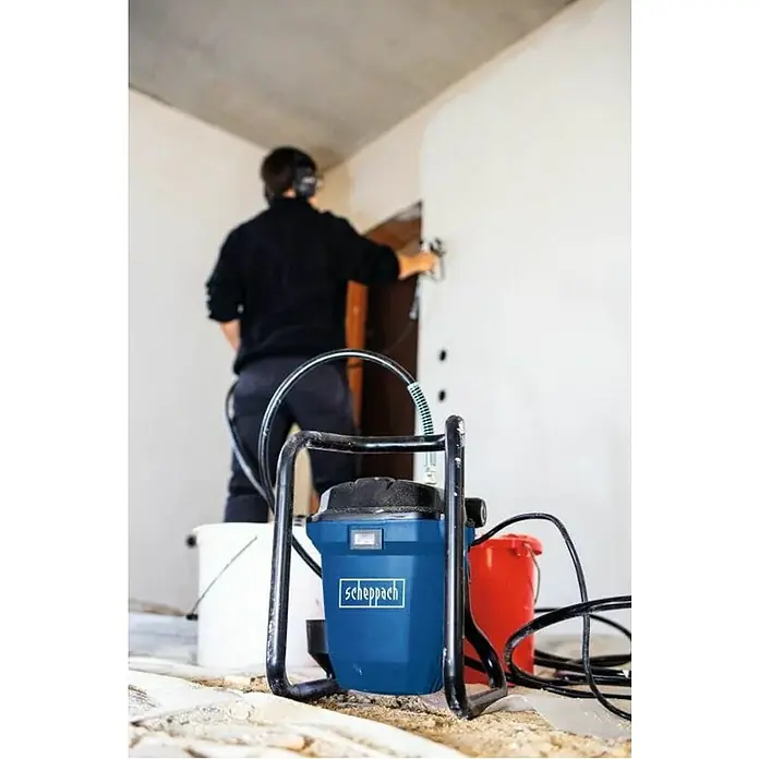 Scheppach Farbsprühsystem PTSA350 - 750 W, Förderleistung: 1,1 l/min - Ein Mann benutzt eine Scheppach Farbspritzpistole, um eine Wand zu streichen. Das Gerät steht im Vordergrund neben zwei Eimern.