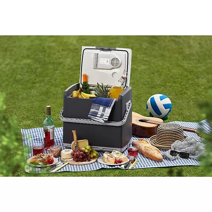 AEG Kühlbox KK28 - Fassungsvermögen: 28 l, Grau - Graue und schwarze elektrische Kühlbox, offen bei einem Picknick, gefüllt mit Obst und Getränken.