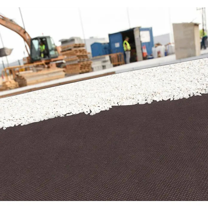 Faura Tejido contra malas hierbas Geotextil - 10 x 1,6 m, Marrón - Imagen de construcción con grava enrollada sobre tela negra, con una excavadora al fondo. Ideal para proyectos y estabilización segura del suelo.