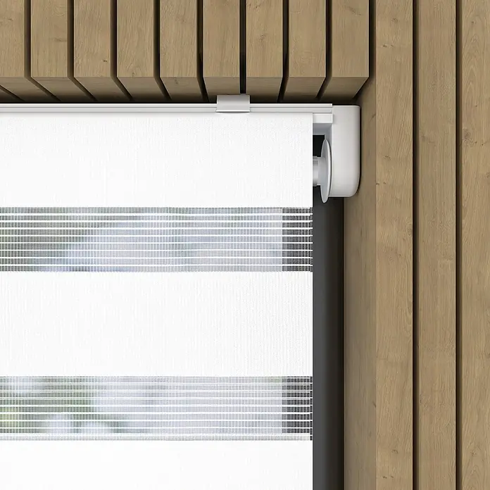 Doppelrollo BasicB x H: 45 x 150 cm, Weiß - Nahaufnahme einer weißen Rolljalousie mit abwechselnden transparenten und blickdichten Streifen vor einem Holzhintergrund.