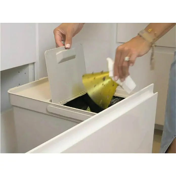 Juego de recambio de conos Cactus - Protección contra: Insectos voladores - Una persona vacía una bolsa de basura amarilla en un cubo de basura blanco de doble compartimento con tapa, en una cocina.