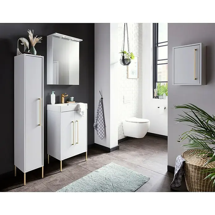 Schildmeyer Sarah Highboard - 25 x 30 x 154,7 cm, Kreideweiß, Matt - Elegantes Badezimmer-Set mit weißen Möbeln, goldenen Griffen und Spiegel. Moderne Toilette an der Wand. Handtuch und Pflanze dekorieren den Raum zusätzlich.