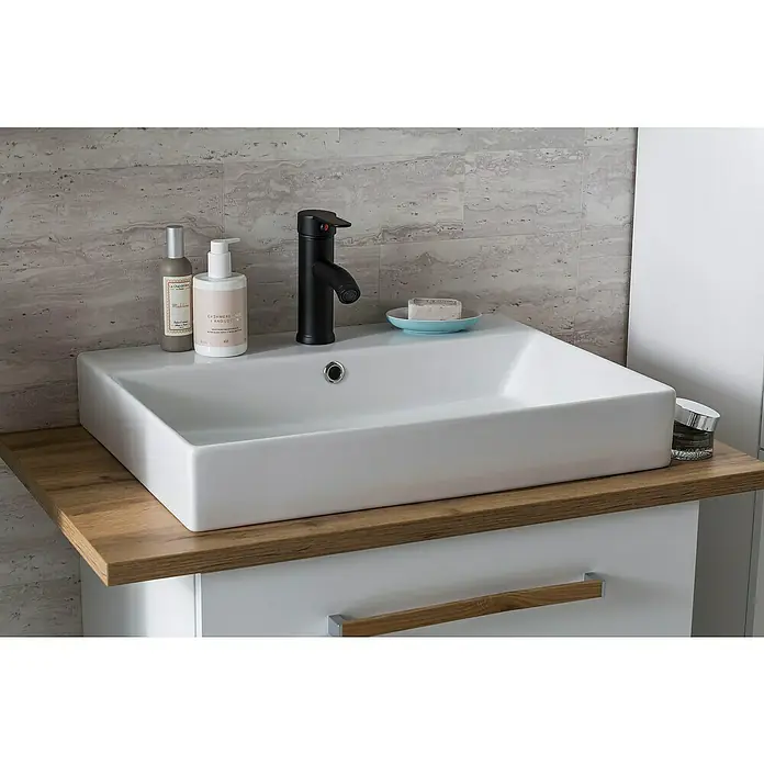 Schildmeyer Duo Badmöbel-Set - Gesamtbreite Badmöbel: 82,2 cm, Kreideweiß/Eiche, Matt - Nahaufnahme eines modernen Waschbeckens mit Armatur, Seife, Lotion und anderen Badutensilien auf einem hölzernen Waschtisch.