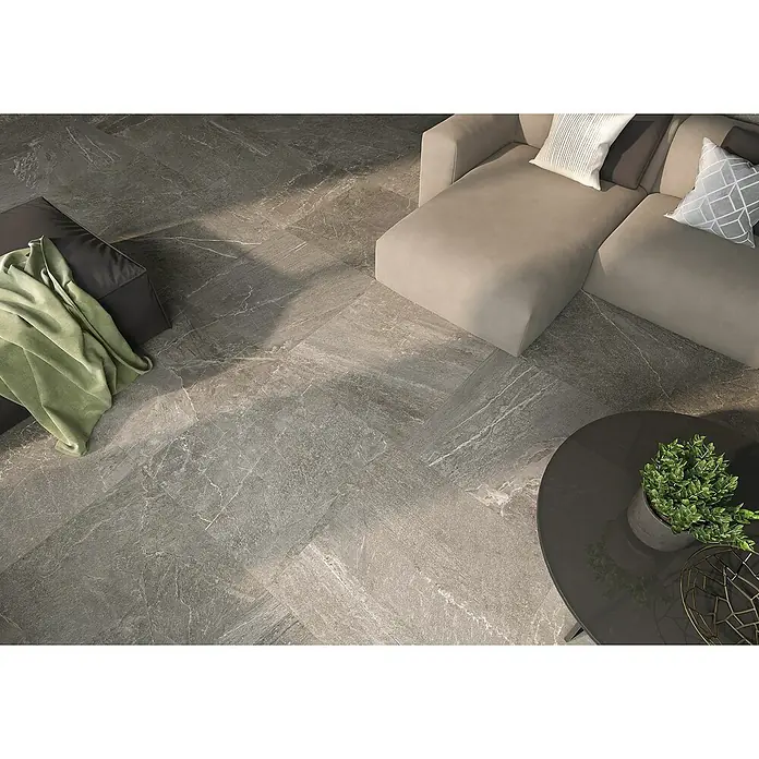 Halcón Pavimento porcelánico Tempo - 60,5 x 60,5 cm, Dark, Mate, Clase 3 Antideslizante - Elegantes baldosas de suelo grises con efecto mármol crean un ambiente elegante en la sala de estar con sofá y mesa.