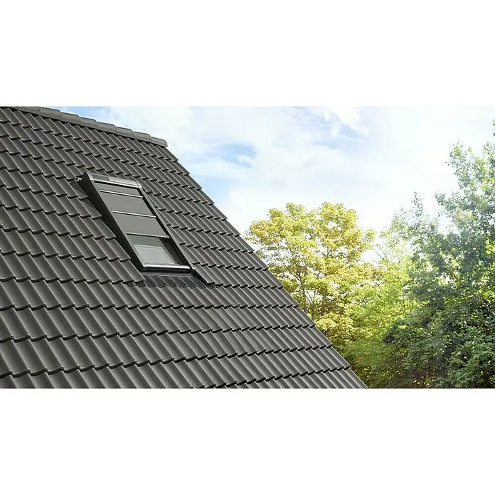 Velux Hitzeschutz-Markise Solar SSS - Passend für Fenstertyp: GGU, GGL, GPU, GPL, GHU, GHL, Passend für Fenstergröße: PK06, P06 - Detailaufnahme eines Daches mit dunklen Ziegeln und einem eingebauten Dachfenster, das für Tageslicht im Innenraum sorgt.