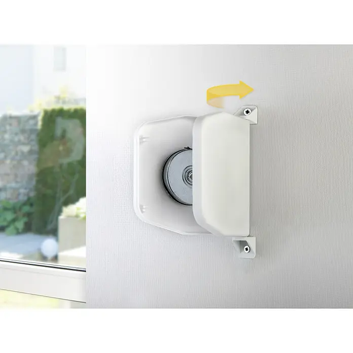 Schellenberg Recogedor atornillable Mini - L x An x Al: 140 x 22 x 165 mm, Anchura de la correa: 14 mm, Blanco, Giratorio 180° - Primer plano de una caja de persiana blanca en una pared, que se puede abrir lateralmente, con una flecha amarilla que indica la dirección de apertura.