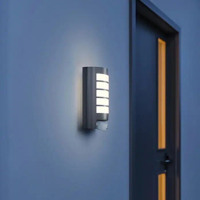 Steinel Sensor-Außenleuchte L 12 anthrazit - 60 W, 10,8 x 15,5 x 27,2 cm, Anthrazit/Weiß, IP44 - Eine moderne graue Außenwandleuchte mit Bewegungsmelder und hellem Licht sorgt für Sicherheit und Stil an der Hauswand.