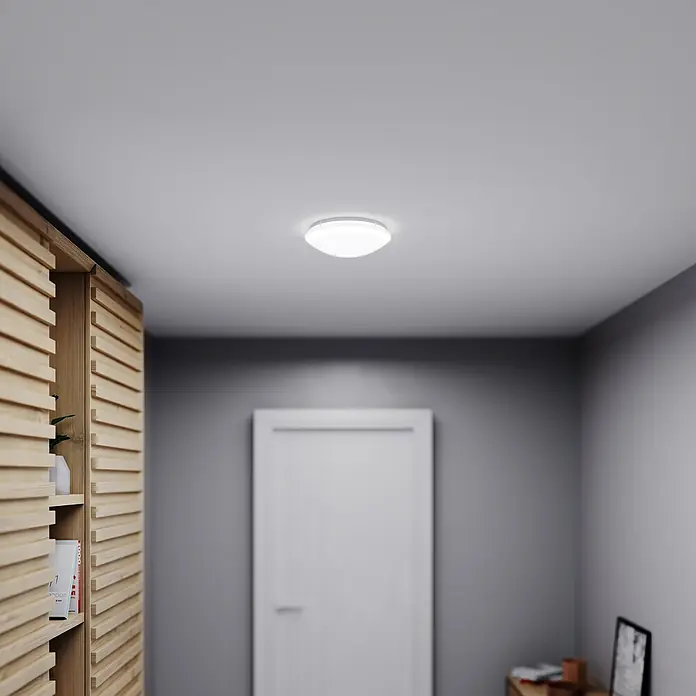 Steinel Sensor-Wand- & Deckenleuchte RS 16 L weiß - 60 W, L x B x H: 27,5 x 27,5 x 9,5 cm, Weiß, E27 - Diese Aufnahme zeigt eine moderne LED-Deckenleuchte in einem Flur, die für eine helle und energieeffiziente Beleuchtung sorgt.