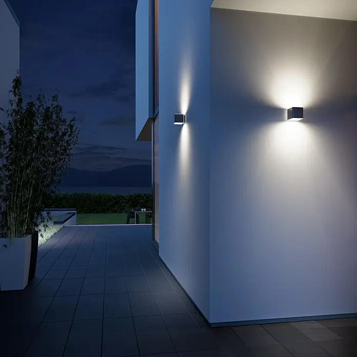 Steinel LED-Sensor-Außenwandleuchte L 840 SC anthrazit - 9,1 W, L x B x H: 11 x 11 x 13,35 cm, Anthrazit, Warmweiß - Moderne Außenwandleuchten mit quadratischem Design beleuchten eine Terrasse in der Abenddämmerung und setzen architektonische Akzente.