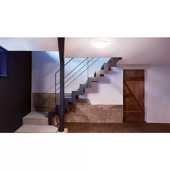Steinel Plafón LED con sensor RS 16 LED S - 9,3 W, Blanco - Escalera flotante moderna de metal oscuro con barandilla, integrada en un interior rústico de piedra y madera.