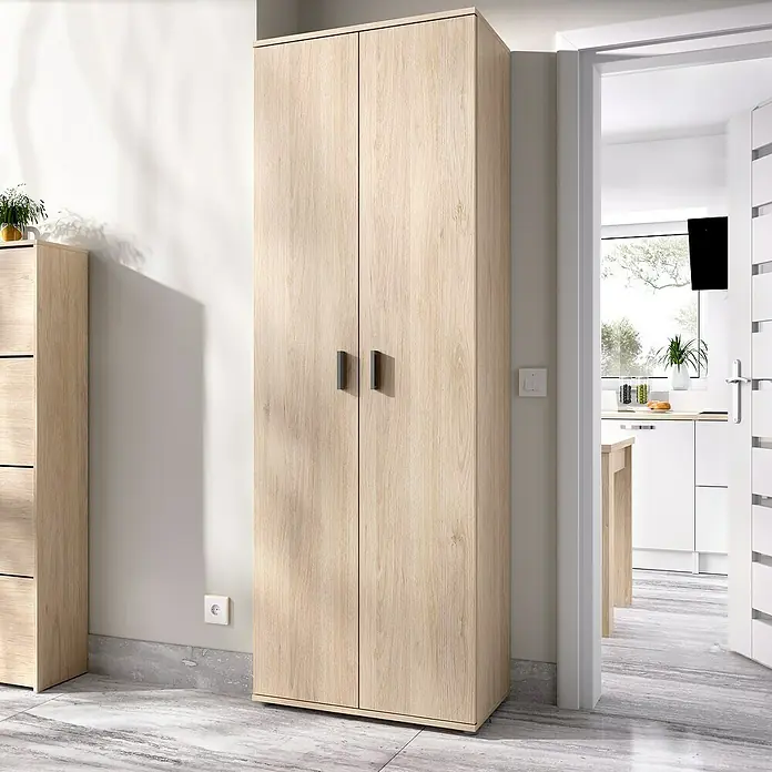 Dekit Armario multiusos de madera Fit - L x An x Al: 35 x 61 x 190 cm, Roble - La imagen muestra un armario de madera moderno con dos puertas, situado en una habitación luminosa. Ofrece mucho almacenamiento.