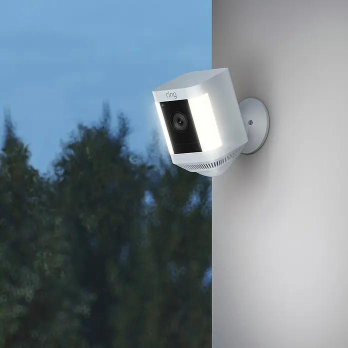 Ring Überwachungskamera Spotlight Cam Plus Battery - Batteriebetrieben, 1.080 Pixel (Full HD), Weiß, B x H: 7,6 x 12,6 cm, Akku - Eine Ring Spotlight Cam ist an einer Wand montiert und beleuchtet den Bereich. Die Kamera bietet Sicherheit und Überwachung für Ihr Zuhause.