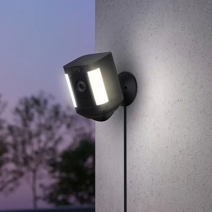 Ring Überwachungskamera Spotlight Cam Plus Plugin - Netzbetrieben, 1.080 Pixel (Full HD), Schwarz, B x H: 7,6 x 12,6 cm, Netzanschluss - Intelligente Ring Flutlichtkamera mit zwei hellen LED-Streifen, montiert an einer Wand für erhöhte Sicherheit.