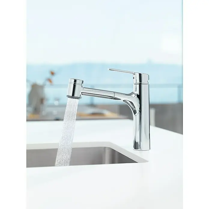 Hansa Ronda SpültischarmaturNiederdruck, Chrom, Glänzend - Verchromter Küchenarmatur mit herausziehbarer Brause, aus der Wasser fließt, auf einer weißen Küchentheke.