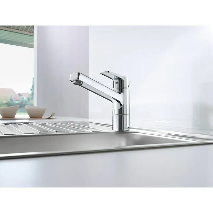 Hansa Twist Spültischarmatur - Chrom, Glänzend - Nahaufnahme einer modernen Küchenarmatur aus Chrom, die auf einer Spüle montiert ist, mit einem Fenster im Hintergrund.
