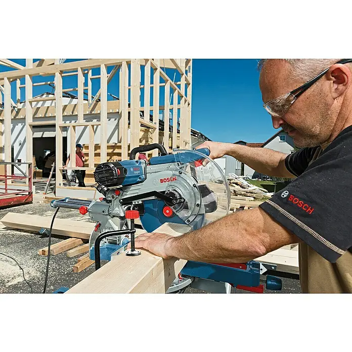 Bosch Professional Sägetisch GTA 2500 W - Belastbarkeit: 180 kg - Ein Bauarbeiter benutzt eine Bosch Kapp- und Gehrungssäge GCM 12 SDE zum Zuschneiden eines Holzstücks auf einer Baustelle.