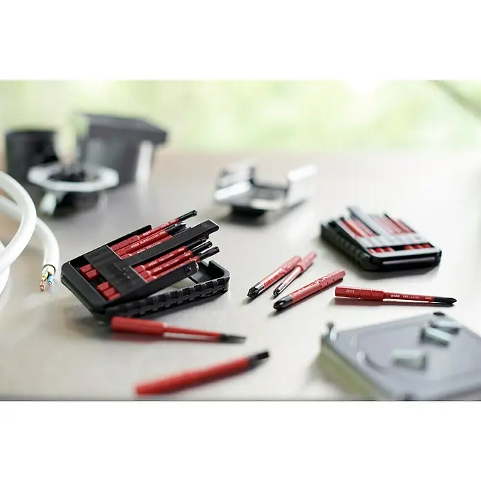 Wiha Bit-Set slimBit electric - 6 -tlg., SL & SL/PZ - Das Bild zeigt ein Wiha-Schraubendreher-Set auf einem Tisch zusammen mit Werkzeugen, wodurch Vielseitigkeit und Präzision betont werden.