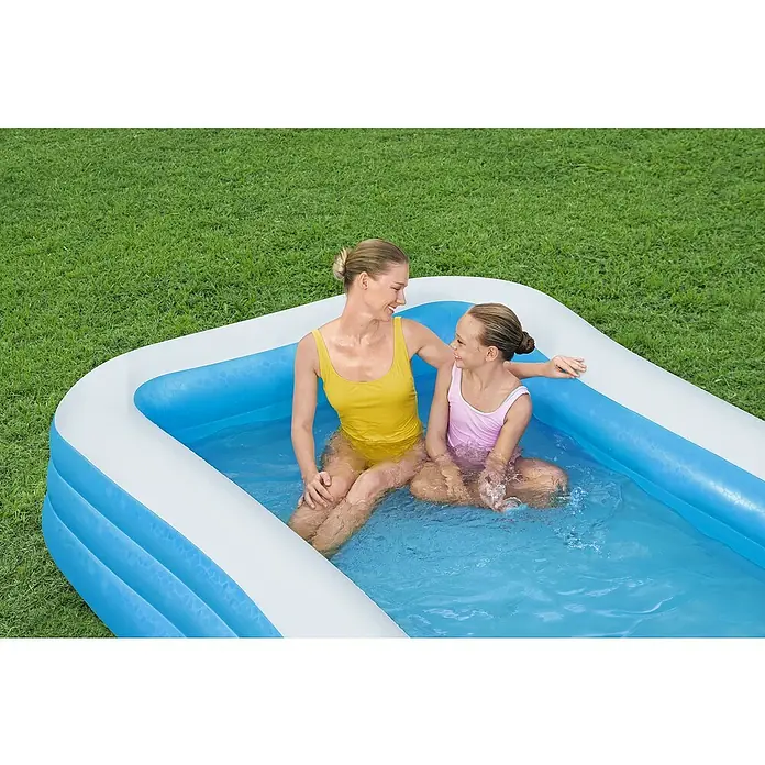 Family Pool - 305 x 183 x 56 cm, Fassungsvermögen: 1.161 l, Blau/Weiß - Eine Frau und ein Kind sitzen in einem aufblasbaren Pool im Garten. Das Produkt ist ein rechteckiger Pool mit blau-weisser Farbe.