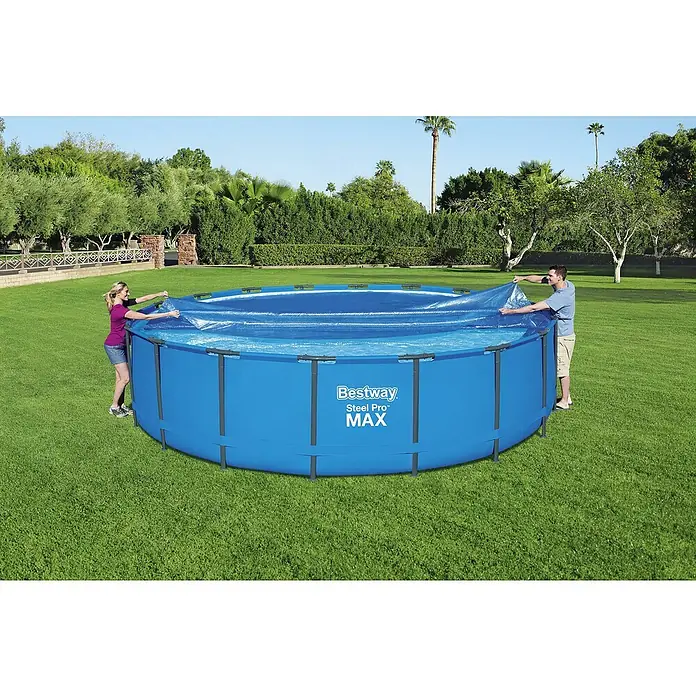Bestway Solarabdeckplane - Durchmesser: 527 cm, Blau - Ein Bestway Steel Pro Max Pool wird von zwei Personen mit einer blauen Plane abgedeckt. Schöne Gartengestaltung im Hintergrund.