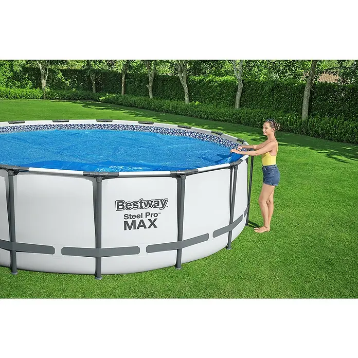 Bestway Solarabdeckplane - Durchmesser: 527 cm, Blau - Ein Bestway Steel Pro MAX Pool im Garten mit einer Frau, die daneben steht. Der Pool ist mit einer blauen Abdeckung versehen.