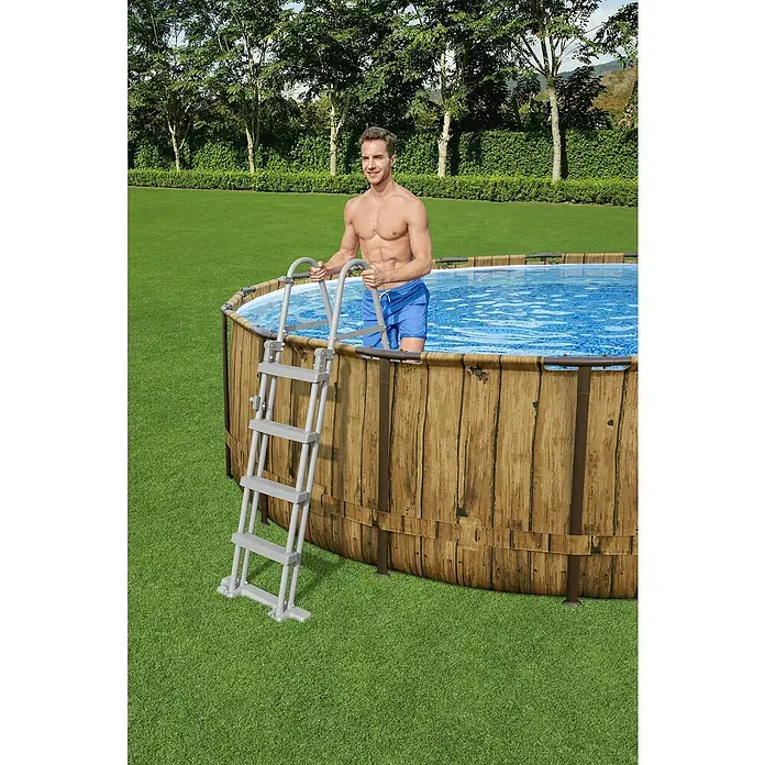 Bestway Flowclear Poolleiter - Passend für: Pools bis 122 cm Höhe, Stahl - Mann steigt mit einer Leiter in einen Pool mit Holzverkleidung.
