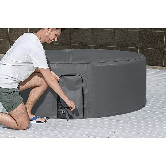 Bestway Lay-Z-Spa Pool-Abdeckplane - Passend für: Runde Whirlpools bis Ø x H: 180 x 66 cm, Ø x H: 180 x 66 cm - Ein Mann kniet neben einem grauen aufblasbaren Whirlpool mit Schutzhülle und passt eine Reißverschlussklappe an.