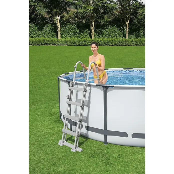 Bestway Flowclear Poolleiter - Passend für: Pools bis 122 cm Höhe, Stahl - Eine Frau steigt über eine Leiter in einen aufblasbaren Pool im Garten. Der Pool ist von einem grünen Rasen umgeben.