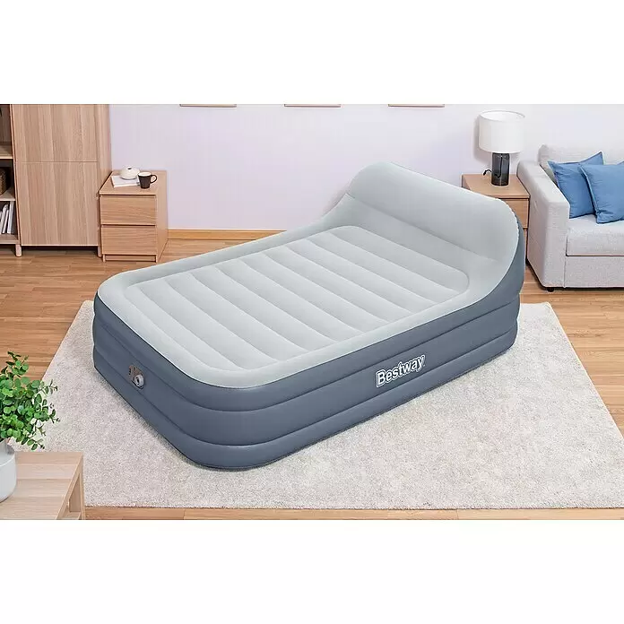 Bestway Luftbett SleekFlow - L x B x H: 226 x 152 x 84 cm, Integrierte Luftpumpe - Ein grau-weißes aufblasbares Luftbett mit horizontalen Rippen und integriertem Kopfteil, auf einem hellen Teppich in einem Raum.